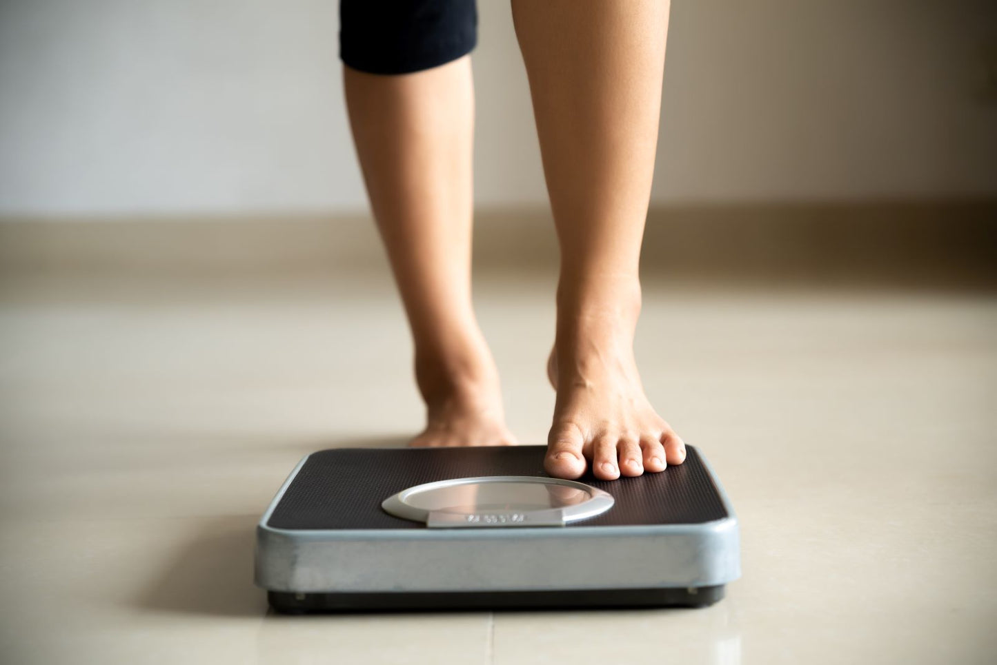 Bare feet stepping onto a bathroom scale, representing weight loss and the role of nutrient levels