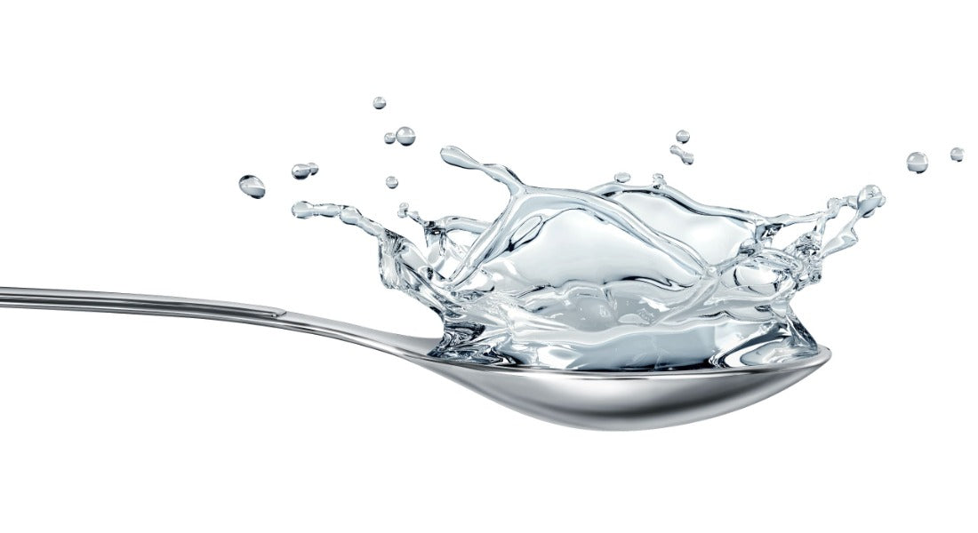 Spoonful of clear silver liquid splashing on a white background, representing colloidal and ionic silver