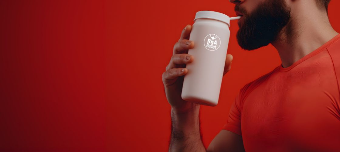 Bearded man in an orange shirt drinking from an RnA ReSet water bottle