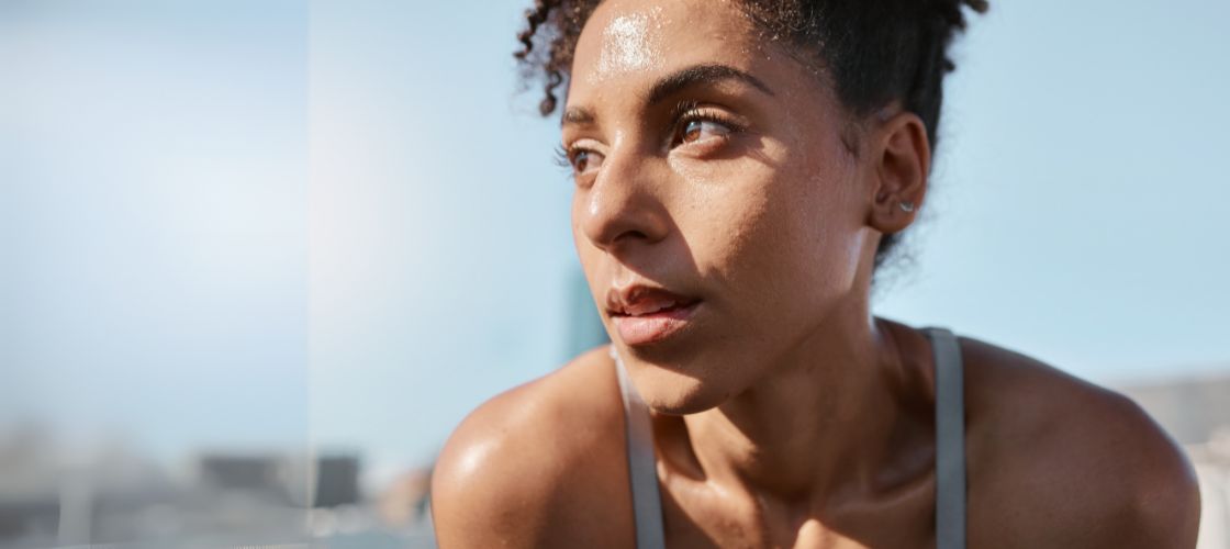 Close-up of a sweating woman athlete outdoors in bright sunlight after exercise