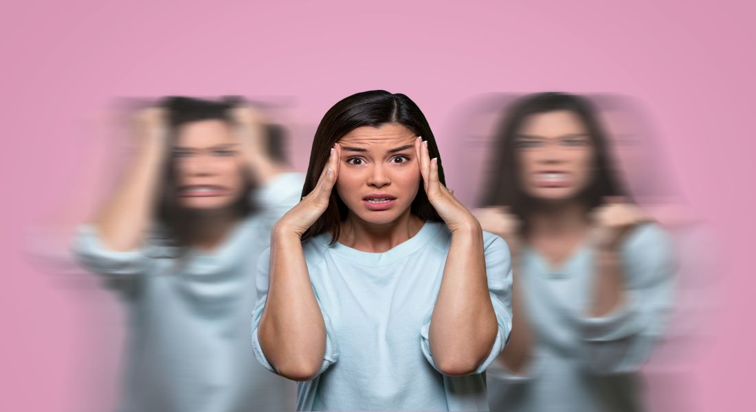 Woman holding her head against a pink background with blurred motion conveying stress