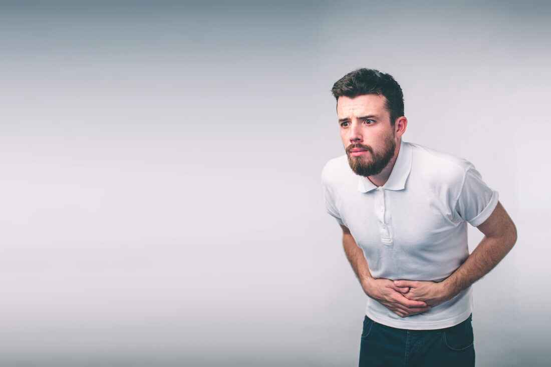 Man bent over holding his stomach in discomfort, representing signs of an unhealthy gut