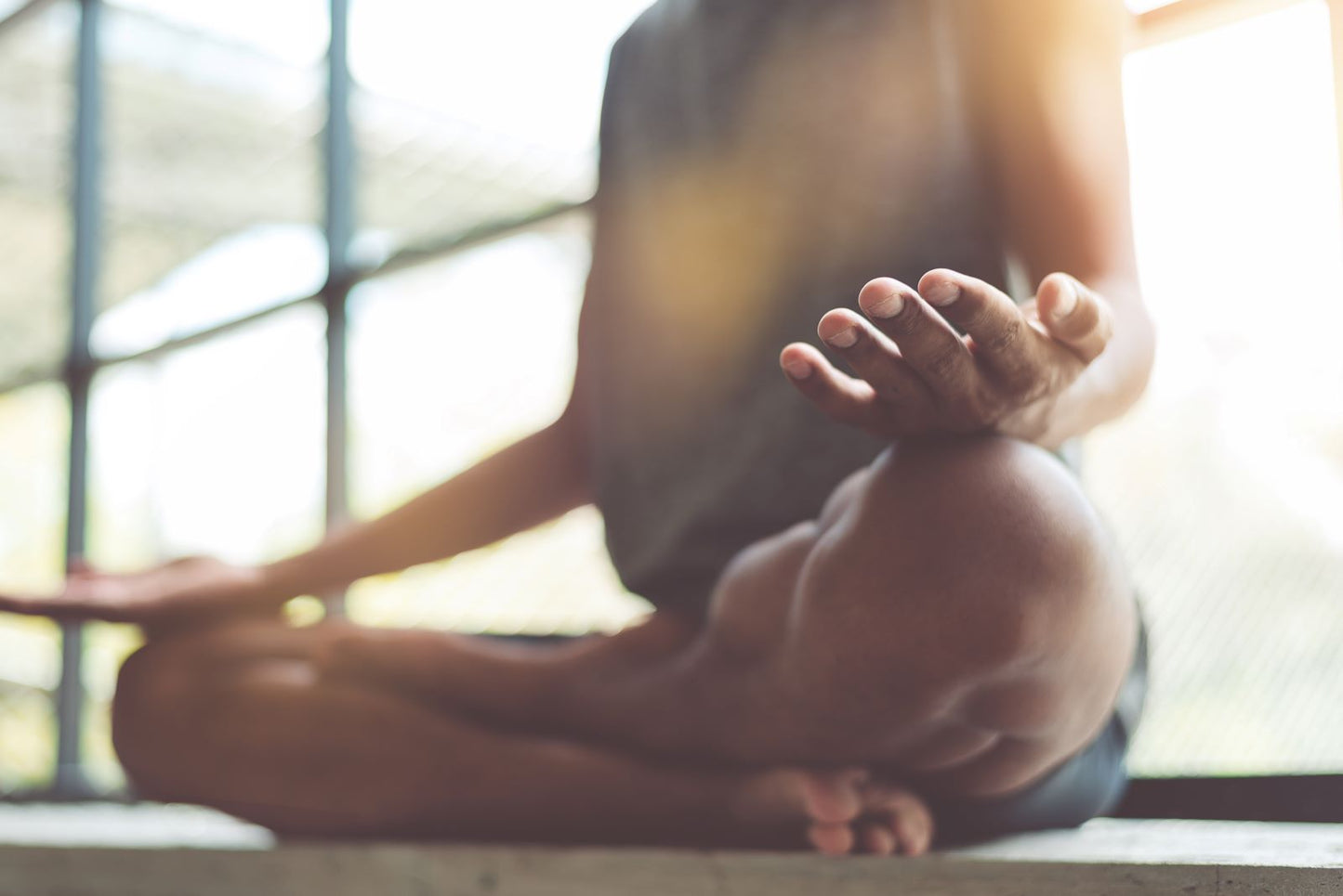 Person sitting cross-legged in a meditation pose by a sunlit window
