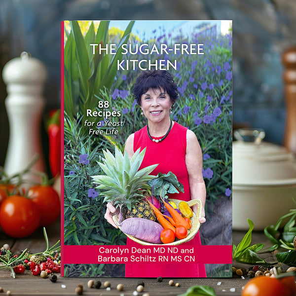 The Sugar-Free Kitchen: 88 Recipes for a Yeast-Free Life by Carolyn Dean MD ND and Barbara Schiltz RN MS CN, cookbook on a kitchen counter with fresh vegetables