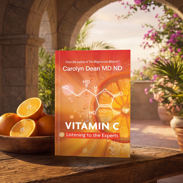 Vitamin C: Listening to the Experts by Carolyn Dean MD ND, book on a wooden table beside a bowl of oranges